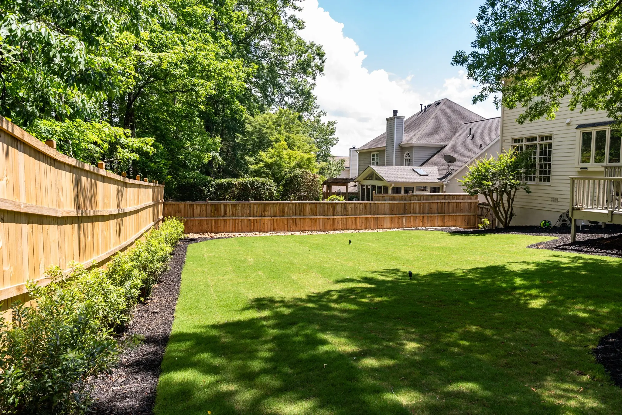 Professional grounds crew performing fall landscaping services Atlanta by clearing leaves, installing fresh pine straw, and aerating a large commercial lawn.