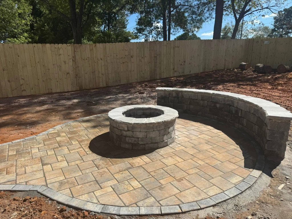 A beautiful custom stone patio and retaining wall built by Atlanta hardscaping services experts in a fall backyard setting.